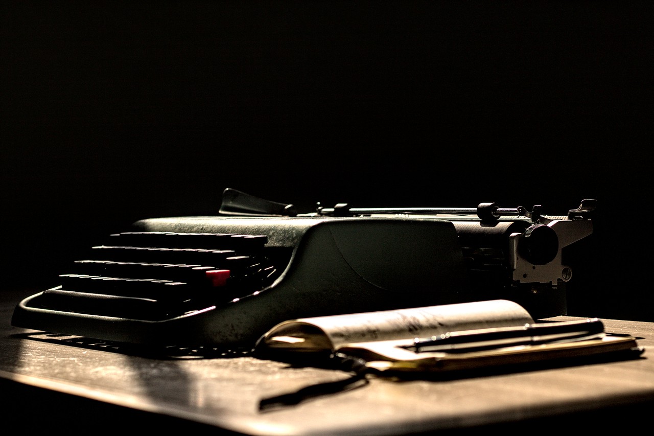 Caderneta aberta sob caneta e máquina de escrever Olivetti Lettera 22