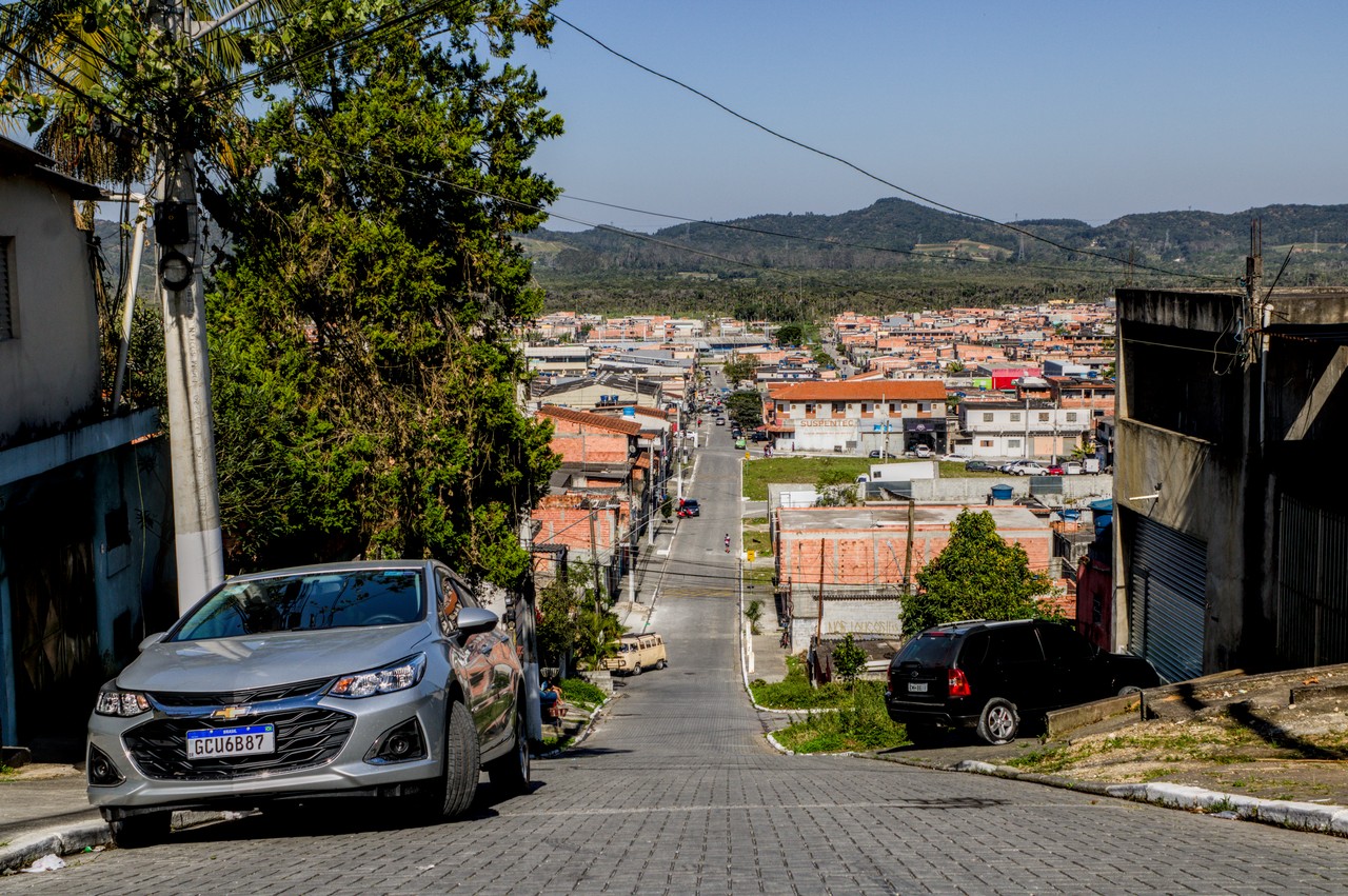 Vista de bairro periférico com borda de cratera ao fundo.