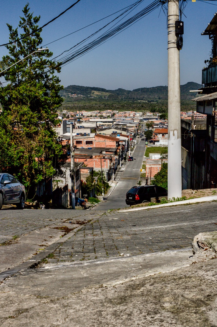 Vista de bairro periférico com borda de cratera ao fundo.