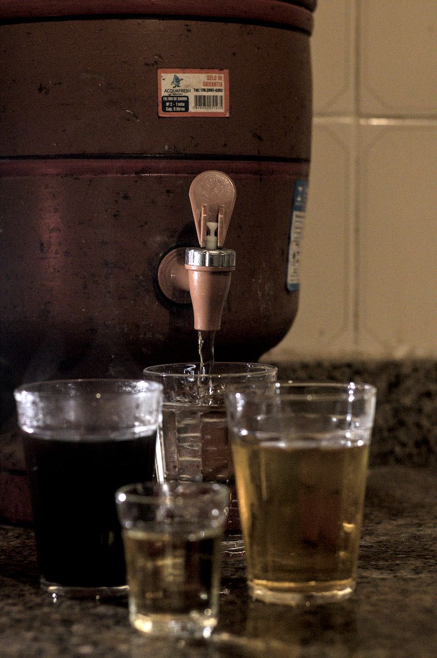 Os vários usos de um copo americano. Copos americanos com diferetes bebidas. Ao fundo, filtro de barro.