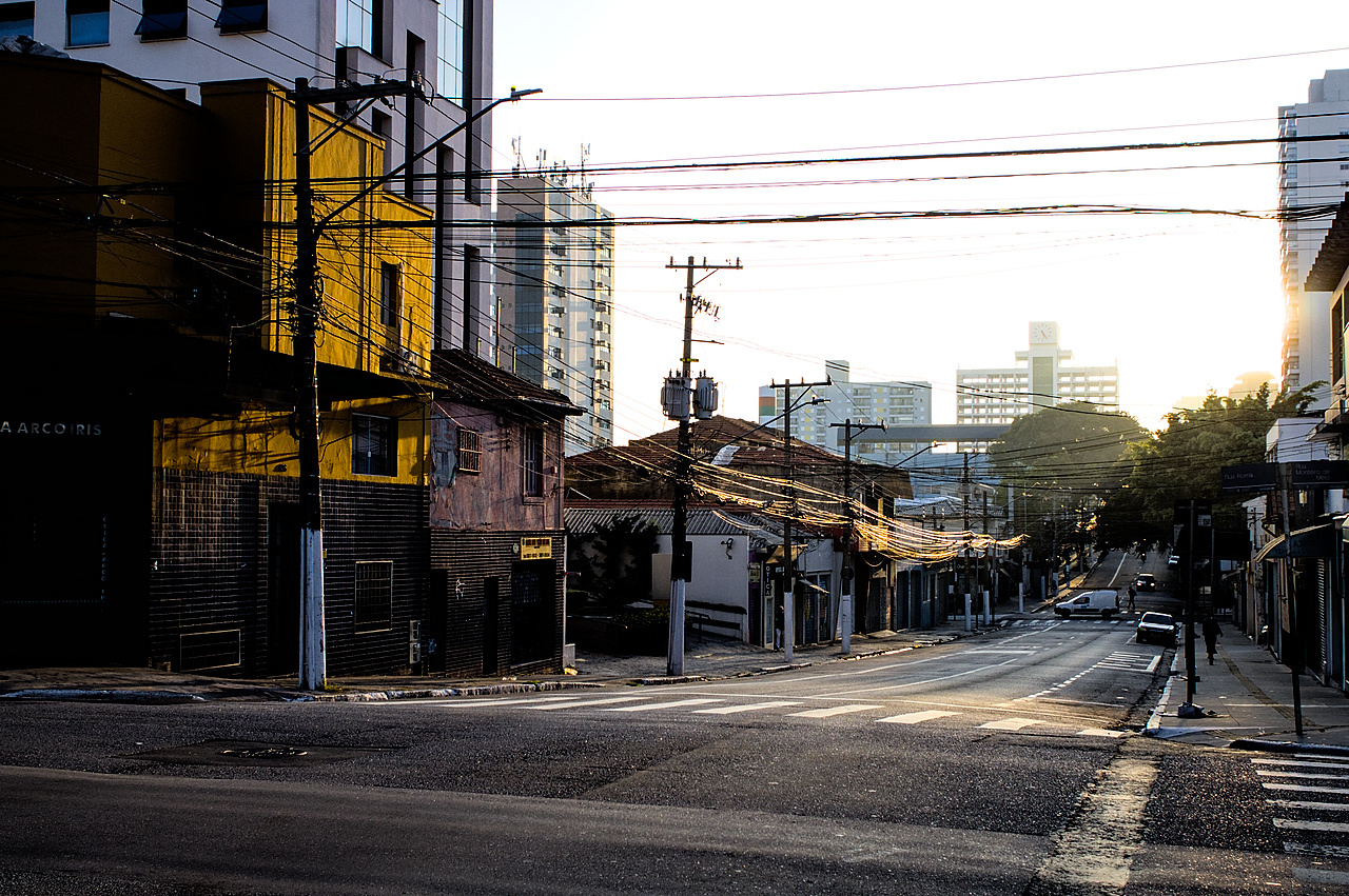 Ladeira côncava. Sol matinal se espalha nos fios ao longo dos postes.