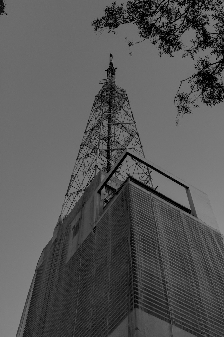 Contra-plongée oblíquo de torre metálica sobre prédio.